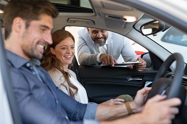 couple buying car with salesman